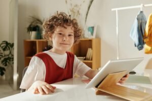 Cheerful child enjoying distance learning with tablet indoors.